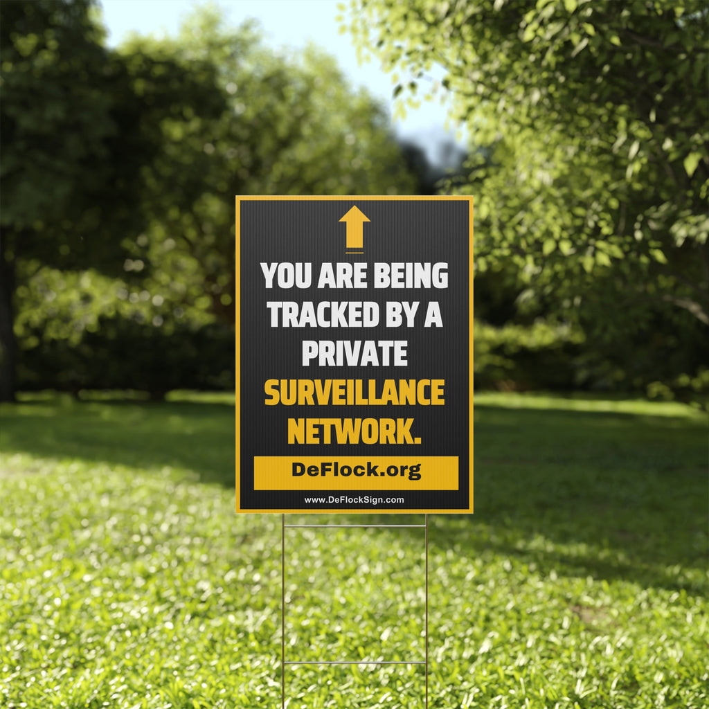 Yard sign with an arrow pointing upwards, and a message that says "You are being tracked by a private surveillance network" to indicate that above the sign is a surveillance camera.