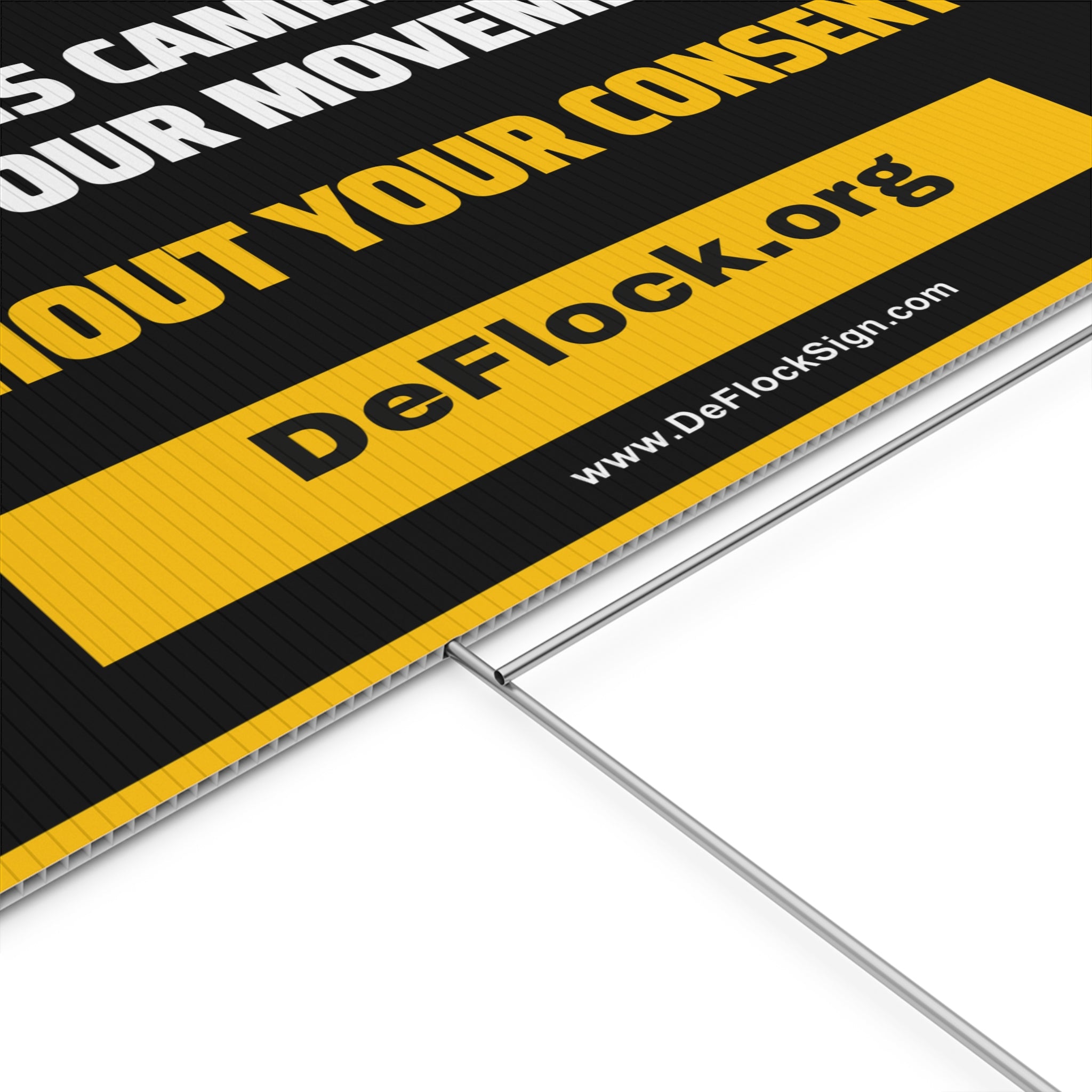 Yard sign with an arrow pointing upwards, and a message that says "This Camera Logs Your Movements Without Your Consent" to indicate that above the sign is a flock camera.
