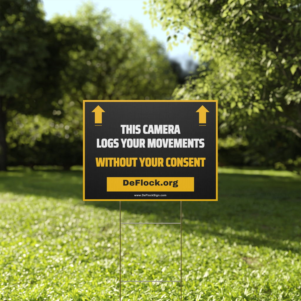 Yard sign with an arrow pointing upwards, and a message that says "This Camera Logs Your Movements Without Your Consent" to indicate that above the sign is a flock camera.