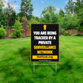 DeFlock Signs yard sign reading "You are being tracked by a private surveillance network" displayed outdoors on a lawn.